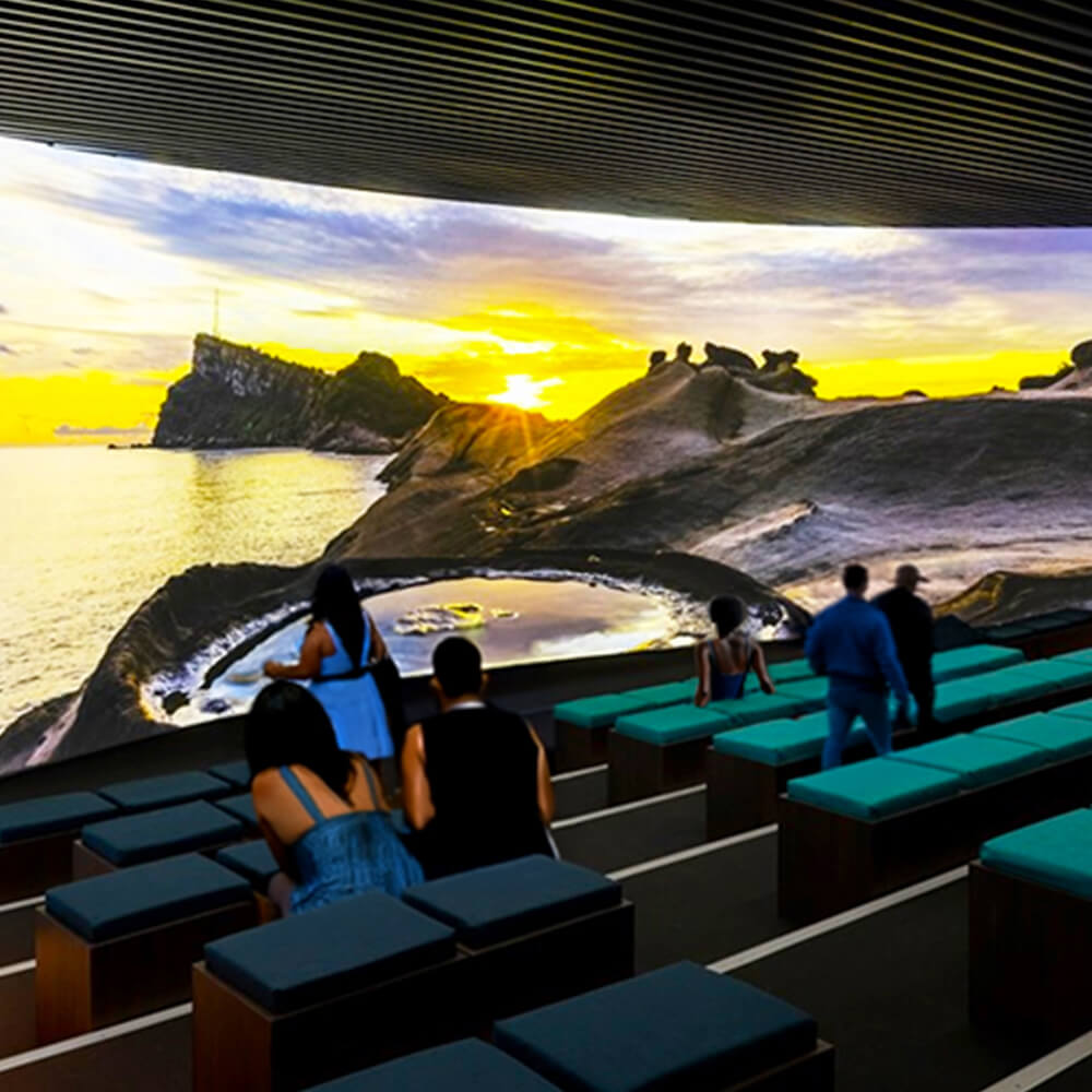 Immersive panoramic theater with 360-degree projection screens showcasing stunning coastal landscapes and nature documentaries. Advanced cinema technology creates breathtaking visual experiences for theme parks, visitor centers, and tourist attractions with wraparound seating and ultra-wide format displays.